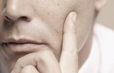 Homen com dedo na bochecha