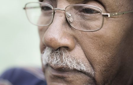 Homem idoso com pele escura sulco nasolabial visível.