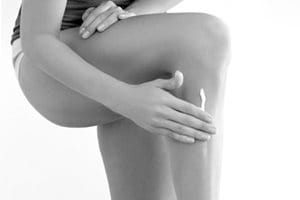 Mulher tocando a perna esquerda