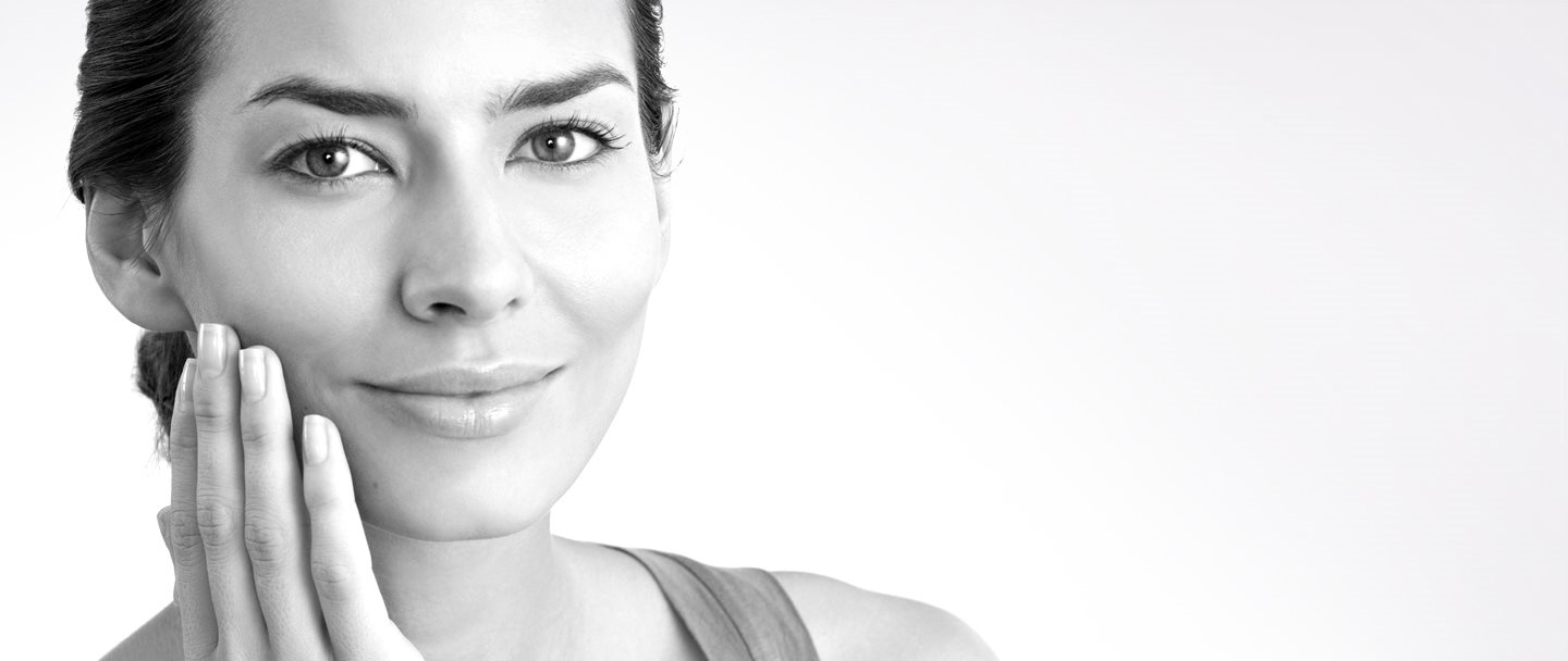 Mulher de meia-idade tocando a sua bochecha direita com a mão